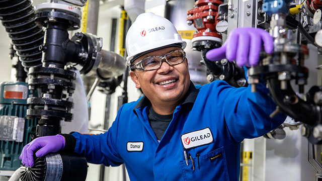 A smiling Gilead employee in a manufacturing facility